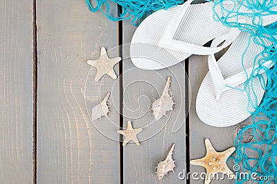 Seashells and white flip flops grey wooden background. Flat lay. Stock Photo