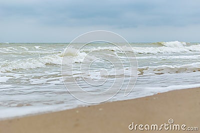 Seashore in cloudy weather. Waves with foam on the water Stock Photo