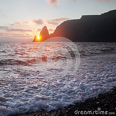 On the seashore setting sun hides behind the powerful coastal cliffs Stock Photo