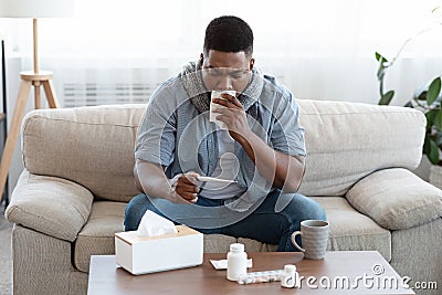 Seasonal Flu. Sick Afro Guy Checking His Body Temperature At Home Stock Photo