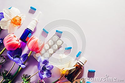 Seasonal spring allergy. Antihistamine pills and nasal spray flat lay with purple pink flowers. Healthcare for allergic Stock Photo