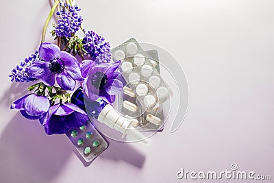 Seasonal spring allergy. Antihistamine pills and nasal spray flat lay with purple pink flowers. Healthcare for allergic Stock Photo