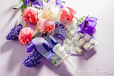 Seasonal spring allergy. Antihistamine pills and nasal spray flat lay with purple pink flowers. Healthcare for allergic Stock Photo