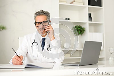 Experienced confident senior doctor with grey hair during phone call Stock Photo