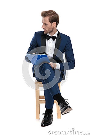 Seated attractive man is writing on notepad while looking away Stock Photo