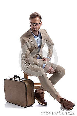 Seated cool fashion model resting his hands on his lap Stock Photo