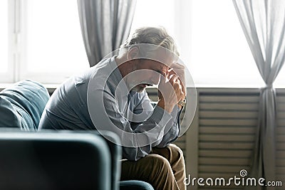 Seated on couch hunched old man looking desperate and lonely Stock Photo