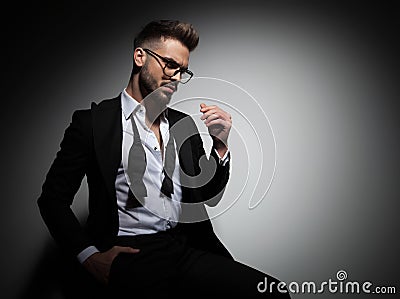 Seated elegant man in tuxedo and undone bowtie Stock Photo