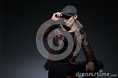 Seated man fixing hat with nonchalant attitude Stock Photo