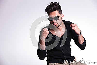 Seated young man pulling his collars Stock Photo