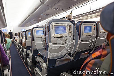 Seating space with multimedia screens economy class airplane cabin Stock Photo