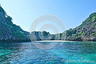 Secluded beach in Thailand. A semicircular rocky island and an aquamarine Andaman Sea enclose a strip of white, clean sand. Stock Photo