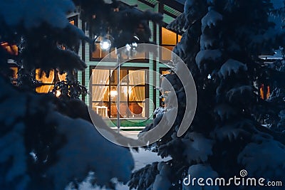 A secluded window deep in the winter forest. Cottage among the pine trees. Stock Photo