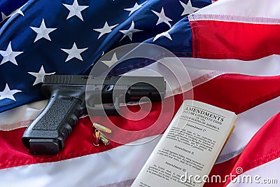 The second amendment and gun control in the US, concept. Handgun, bullets, and the american constitution on the USA flag Stock Photo