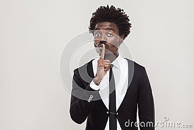 Secret or quiet concept. African businessman showing shh sign at Stock Photo