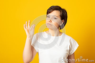Woman zips her mouth shut, promises to keep secret, has gossip safe, holds fingers near cheek, makes promise, hides information. Stock Photo