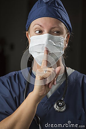 Secretive Female Doctor with Finger in Front of Mouth Stock Photo