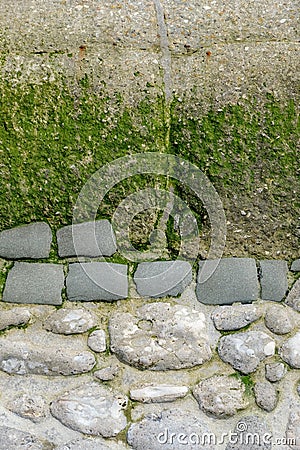 Section of a decorative weathered old wall by the sea in Normandy, stone in part concrete, with algae and moss, copy space, space Stock Photo