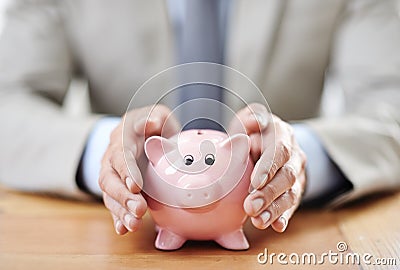 Securing his assets. Cropped image of a businessmans hands covering his piggybank. Stock Photo