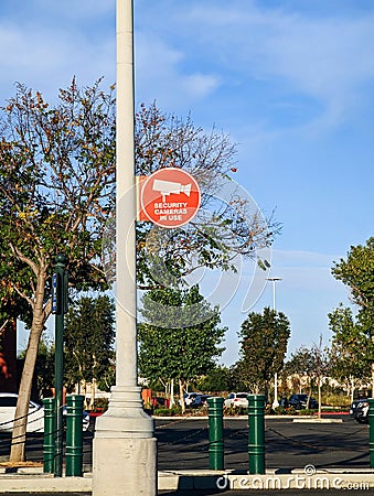 Security cameras in use sign on parking lot light pole Stock Photo