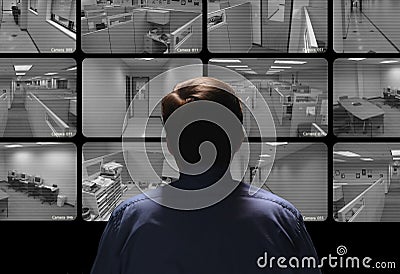 Security guard conducting surveillance by watching several security monitors Stock Photo