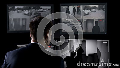 Security guard in earphones watching robbery attempt on surveillance cameras Stock Photo