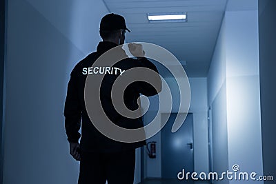 Security Guard With Flashlight In Building Corridor Stock Photo