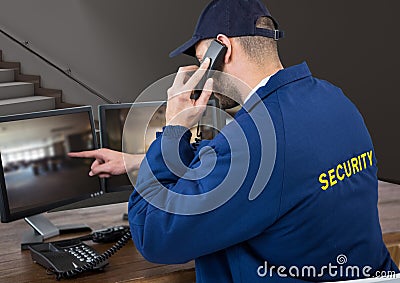 Security guard in his office phoning and pointing something in the screen Stock Photo