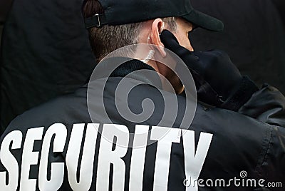 Security Guard Listens To Earpiece, Back of Jacket Showing Stock Photo