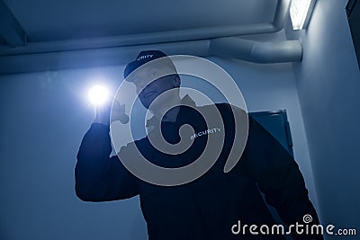Security Guard Searching With Flashlight In Office Stock Photo
