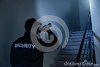 Security Guard Searching On Stairway With Flashlight Stock Photo
