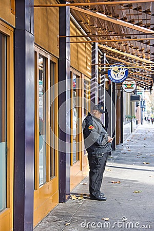 Security Guard Standing at House wall and looking at his mobile in San Jose Editorial Stock Photo