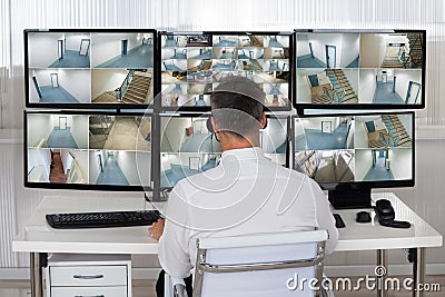 Security System Operator Looking At CCTV Footage At Desk Stock Photo