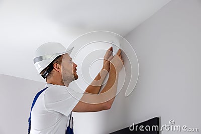 security system technician installing motion sensor on the wall Stock Photo