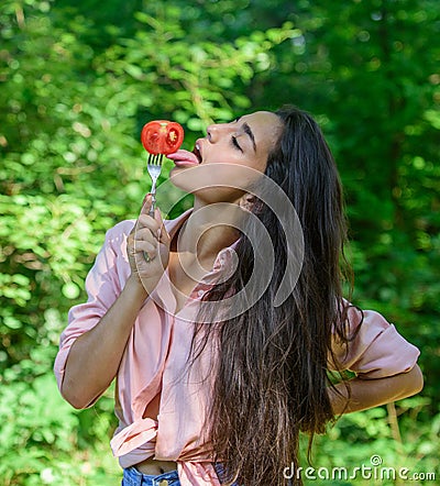 Seductive appetite. Woman full of desire eating tomato. Girl holds fork with juicy ripe tomato. Girl adores ripe Stock Photo