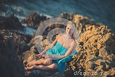 Seductive blond lady woman with naked legs shoulders and arms wearing light blue open dress posing enjoying vacation time on Stock Photo