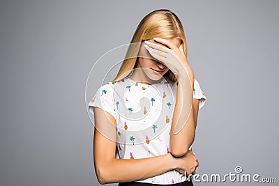 Portrait of young scared woman covering eyes with hands while standing against gray studio background. Confused girl close eyes wi Stock Photo