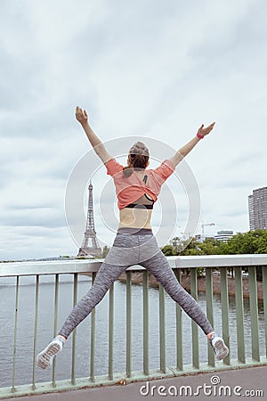 Young woman jogger in sport clothes in Paris, France jumping Stock Photo