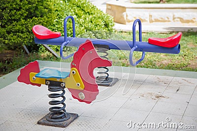 Seesaw on child playground in park. childs horse ride in the playground .Swing on a metal spiral . Spring horse in the playground Stock Photo