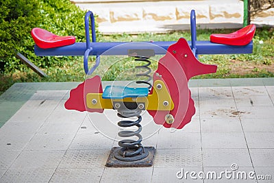 Seesaw on child playground in park. childs horse ride in the playground .Swing on a metal spiral . Spring horse in the playground Editorial Stock Photo