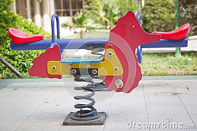 Seesaw on child playground in park. childs horse ride in the playground .Swing on a metal spiral . Spring horse in the playground Stock Photo