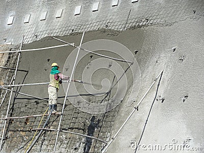 Construction workers are spraying liquid concrete onto the slope surface to form a retaining wall layer. Editorial Stock Photo