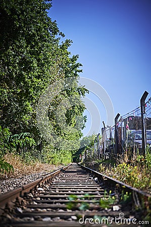 Seldom used, weathered railway line that is gradually overgrown by plants. Stock Photo