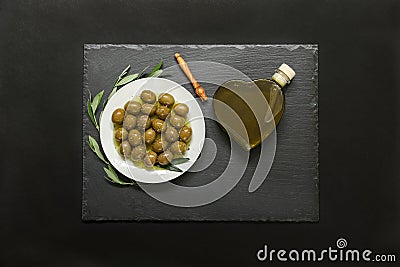 Selected olives in a white plate decorated with natural olive tree branches and olive oil heart bottle. Stock Photo