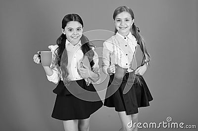 Selecting tea for breakfast. Cute schoolgirls holding cups and books. Small girls enjoying school breakfast. Little Stock Photo