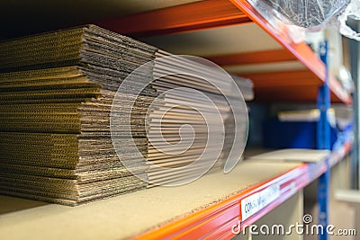 A selection of flat shipping boxes/cartons on a shelf ready to be made up and packed with product. Warehouse, despatch, shipping, Stock Photo