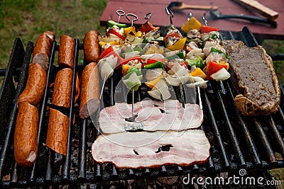 Selection of meat grilling over the coals with spicy sausages, bacon and chicken skewers Stock Photo