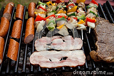 Selection of meat grilling over the coals with spicy sausages, bacon and chicken skewers Stock Photo