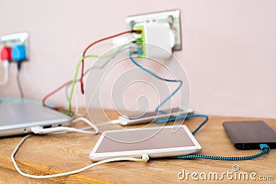 Selection Of Mobile Phones Digital Tablet And Laptop Computer Being Charged At Home Stock Photo