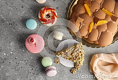 Selection of various pieces of cake - Choux pastries, macarons, chocolate velvet cake on a gray stone background. Stock Photo